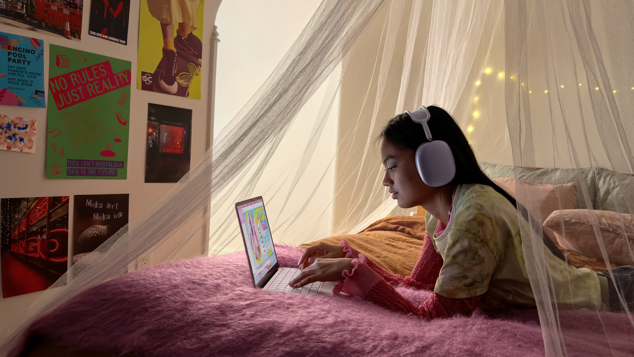 A person wearing headphones using a laptop on a bed.